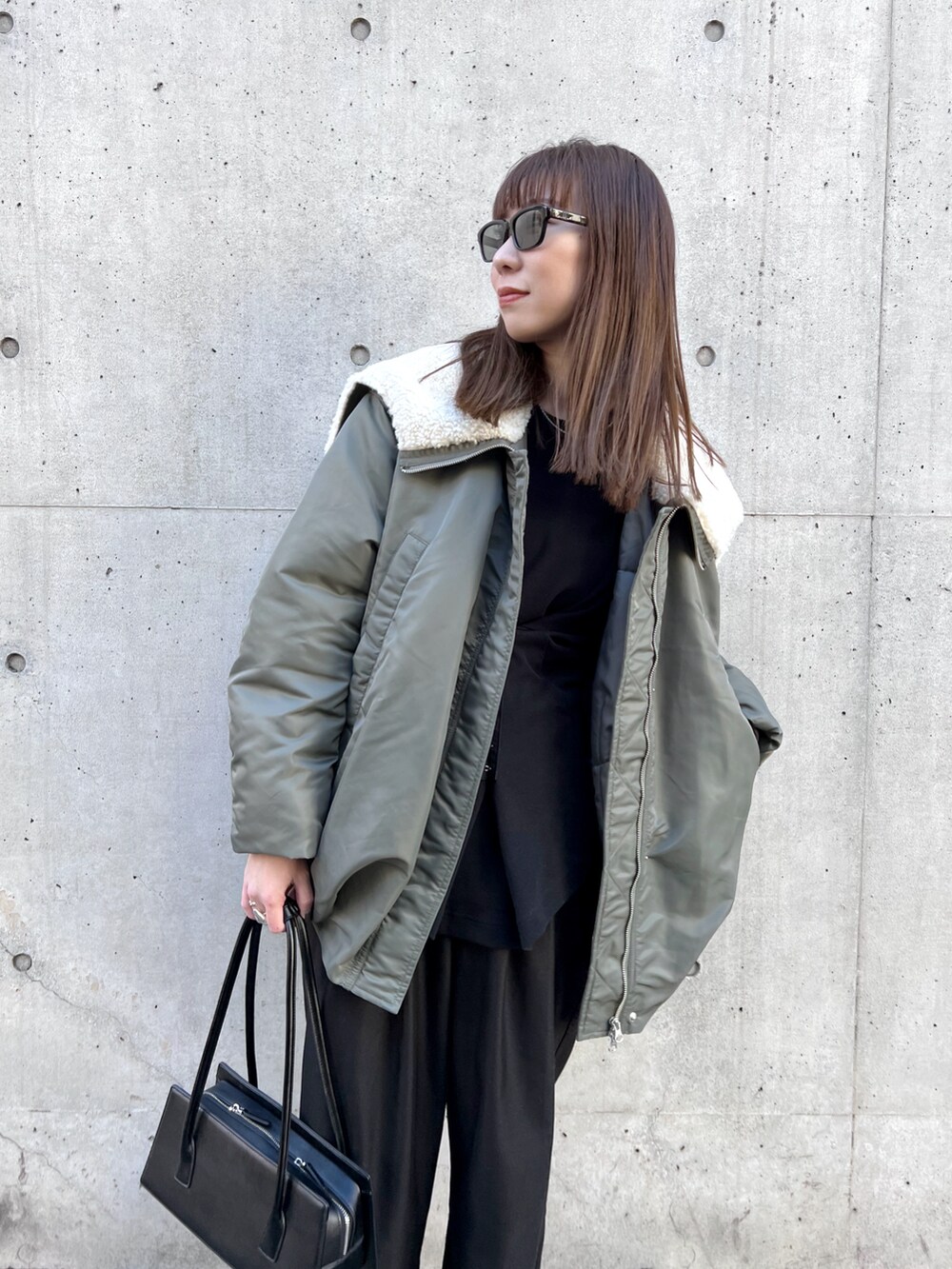 グリーン系のブルゾン、ブラック系のスラックス、ブラック系のハンドバッグを着用したレディースの冬コーディネートの5枚目の写真