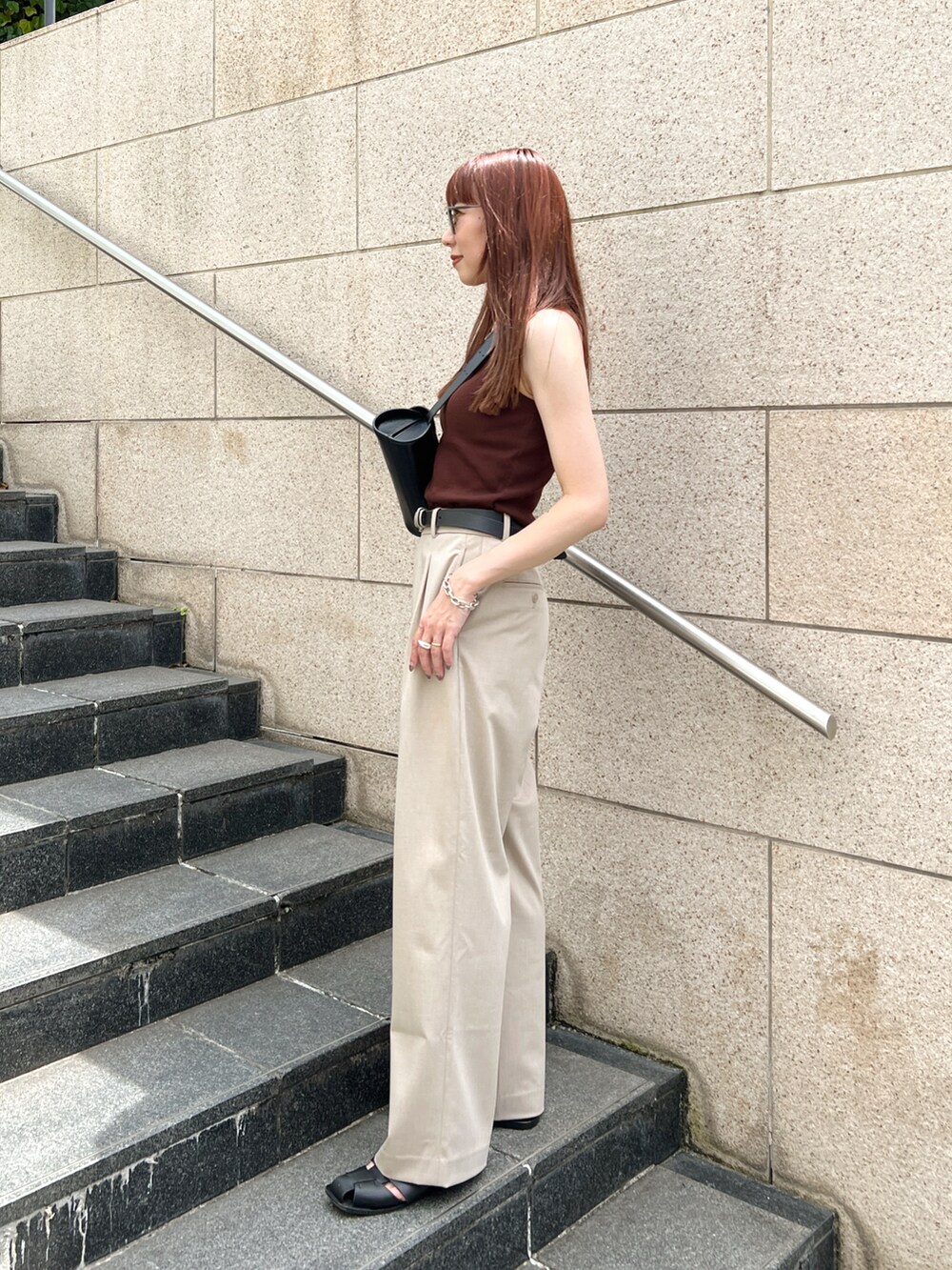 ブラウン系のタンクトップ、ベージュ系のパンツ、ブラック系のショルダーバッグを着用したレディースの夏コーディネートの3枚目の写真