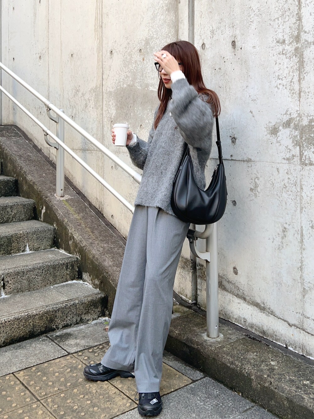 グレー系のニット/セーター、ホワイト系のTシャツ/カットソー、グレー系のパンツを着用したレディースの秋コーディネートの3枚目の写真