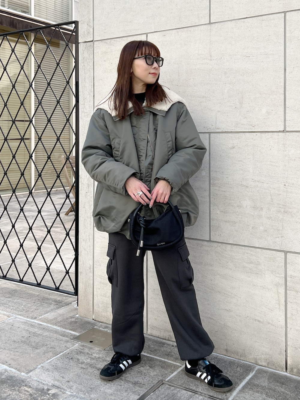 グリーン系のブルゾン、ブラック系のニット/セーター、グレー系のカーゴパンツを着用したレディースの冬コーディネートの2枚目の写真