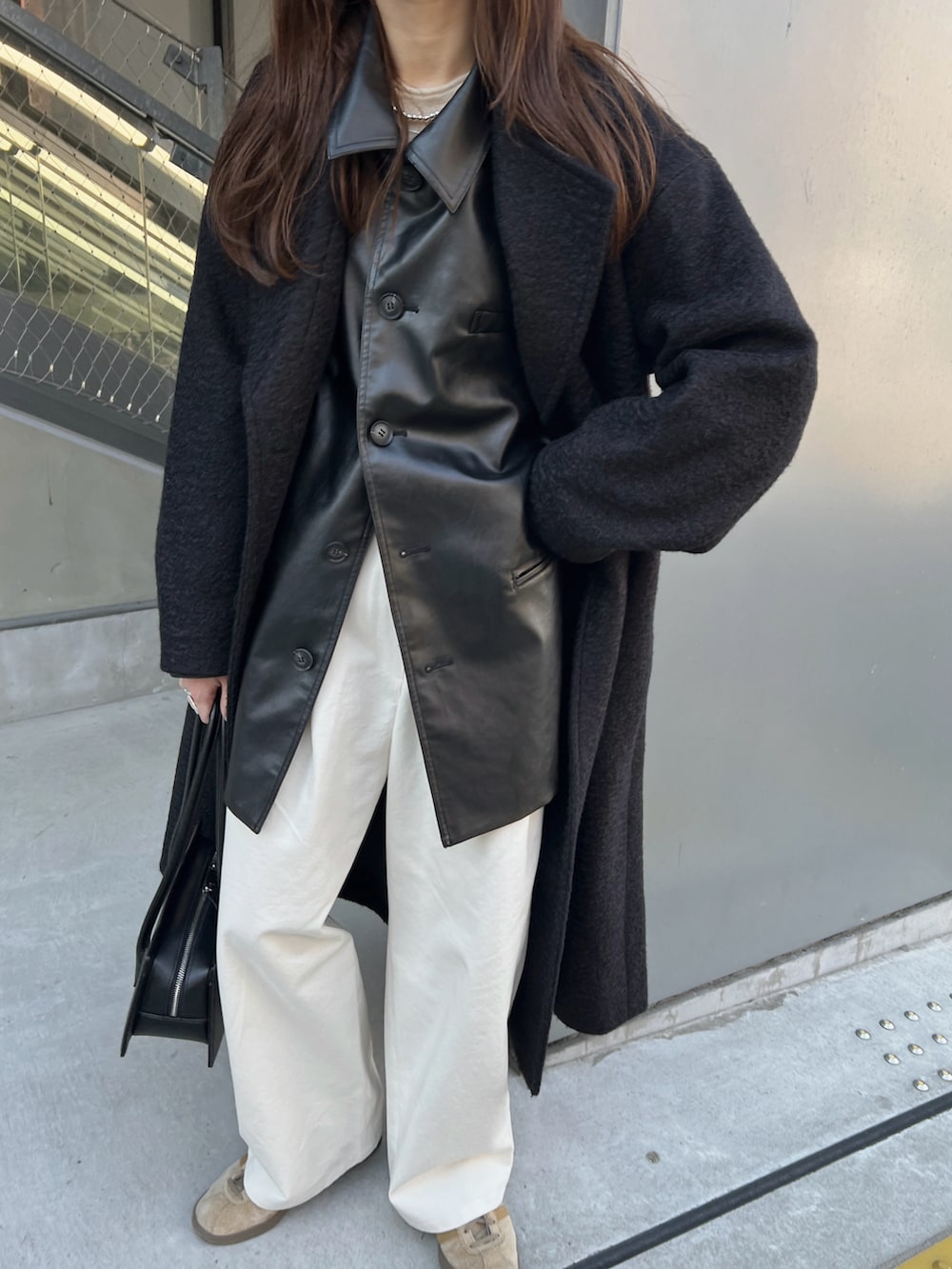 ブラック系のステンカラーコート、ブラック系のその他アウター、ホワイト系のニット/セーターを着用したレディースの冬コーディネートの3枚目の写真