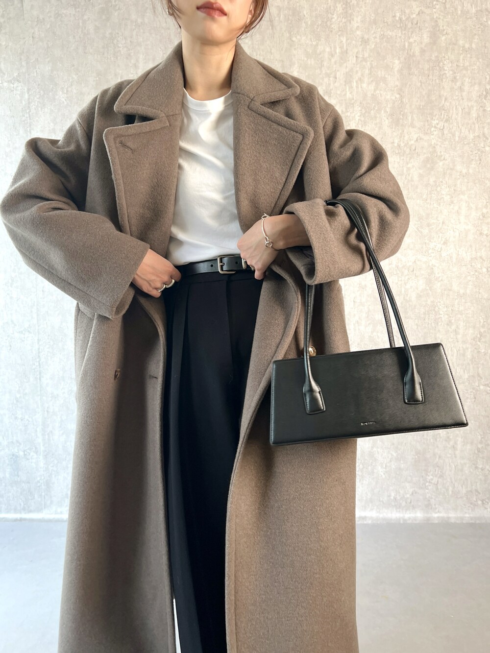 ブラウン系のチェスターコート、ブラック系のその他パンツ、ホワイト系のTシャツ/カットソーを着用したレディースの冬コーディネートの4枚目の写真