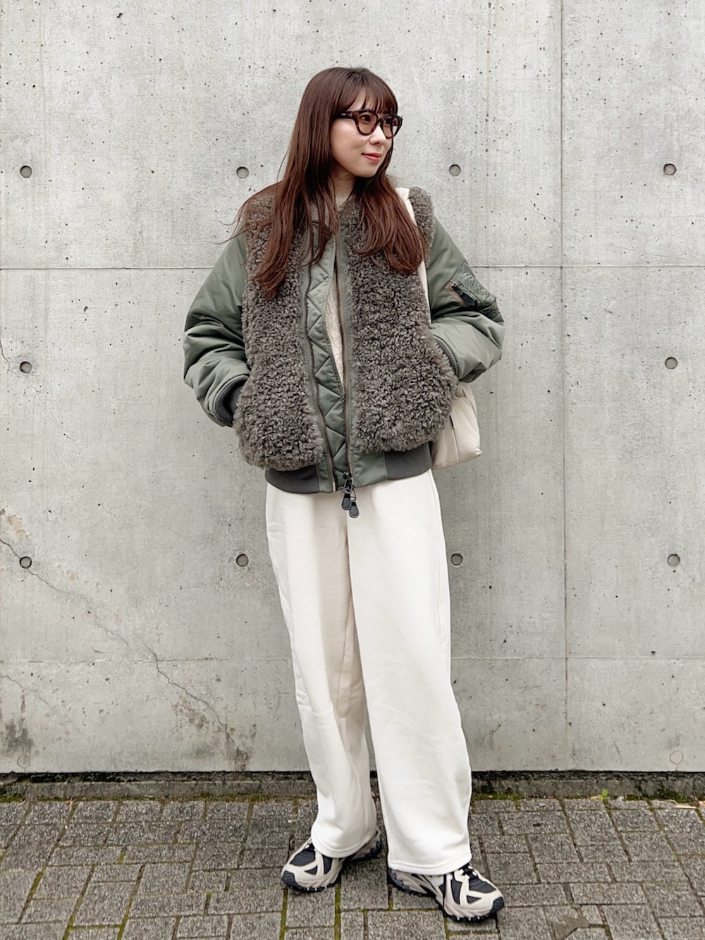 グリーン系のMA-1、ホワイト系のニット/セーター、ホワイト系のスウェットパンツを着用したレディースの冬コーディネートの2枚目の写真