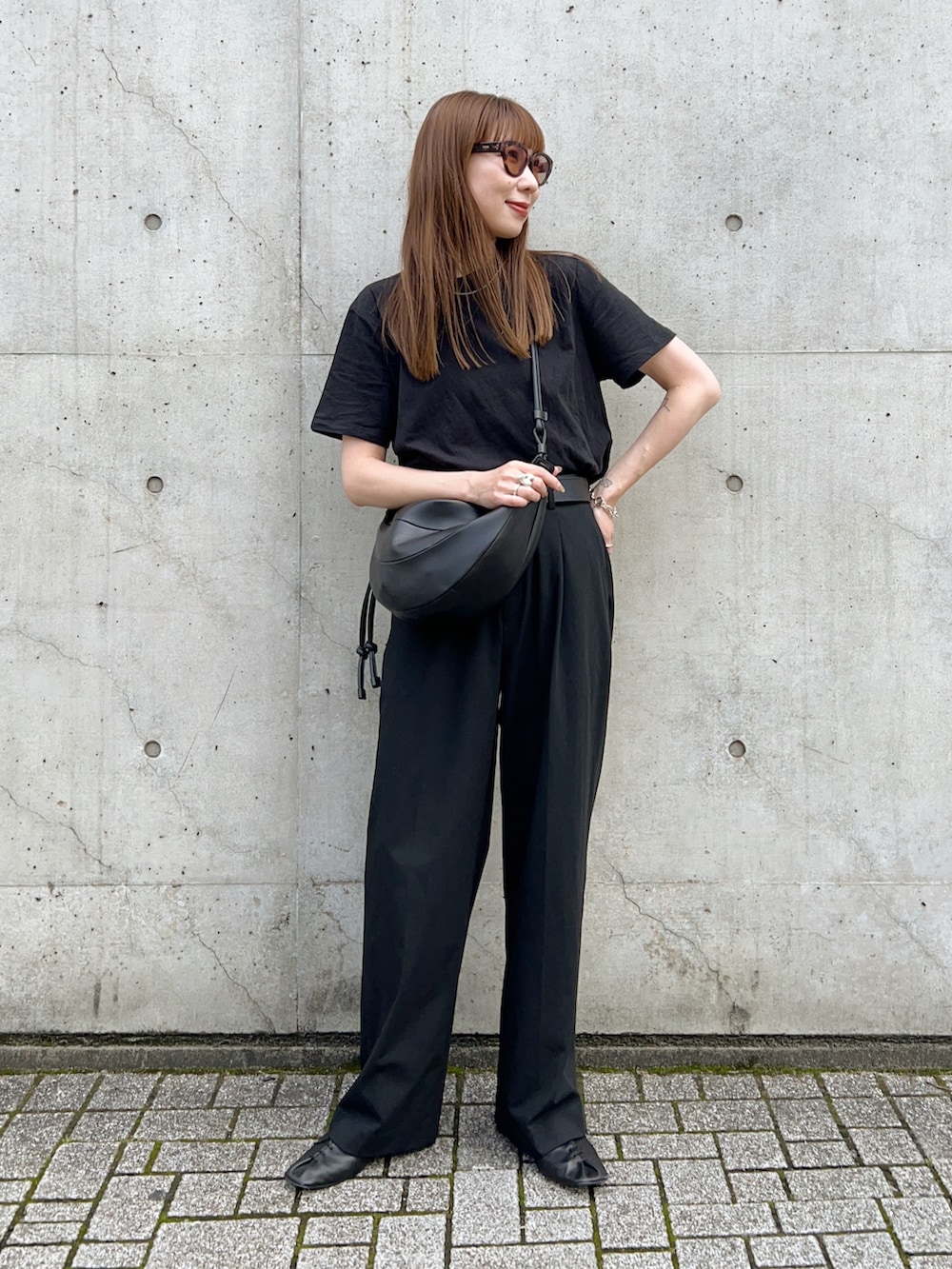 ブラック系のTシャツ/カットソー、ブラック系のスリッポン、ブラック系のパンツを着用したレディースの春コーディネートの2枚目の写真