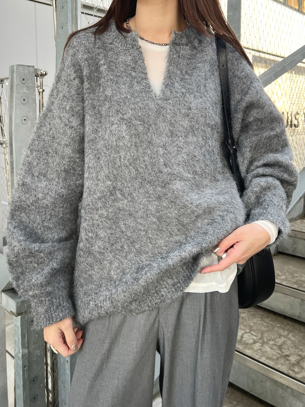 グレー系のニット/セーター、ホワイト系のTシャツ/カットソー、グレー系のパンツを着用したレディースの秋コーディネートの4枚目の写真