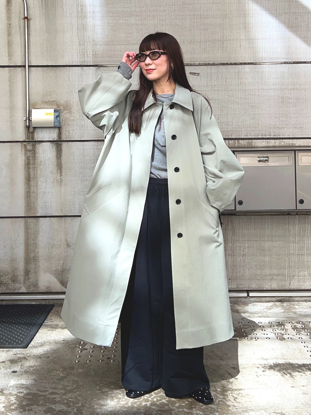 グリーン系のステンカラーコート、グレー系のTシャツ/カットソー、ブラック系のスウェットパンツを着用したレディースの春コーディネートの3枚目の写真