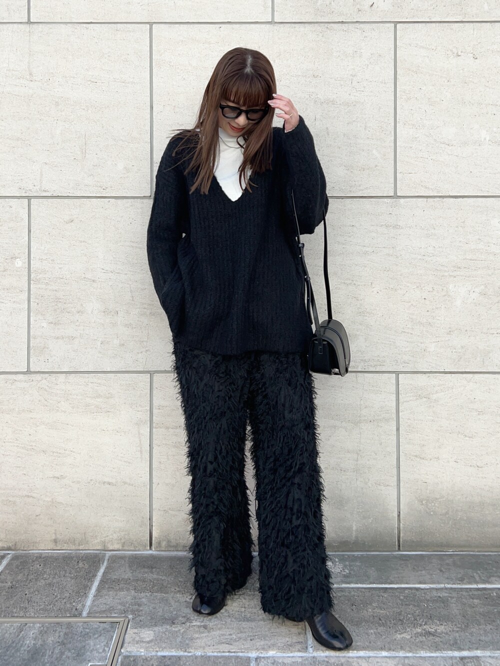 ホワイト系のTシャツ/カットソー、ブラック系のニット/セーター、ブラック系のショルダーバッグを着用したレディースの冬コーディネートの2枚目の写真