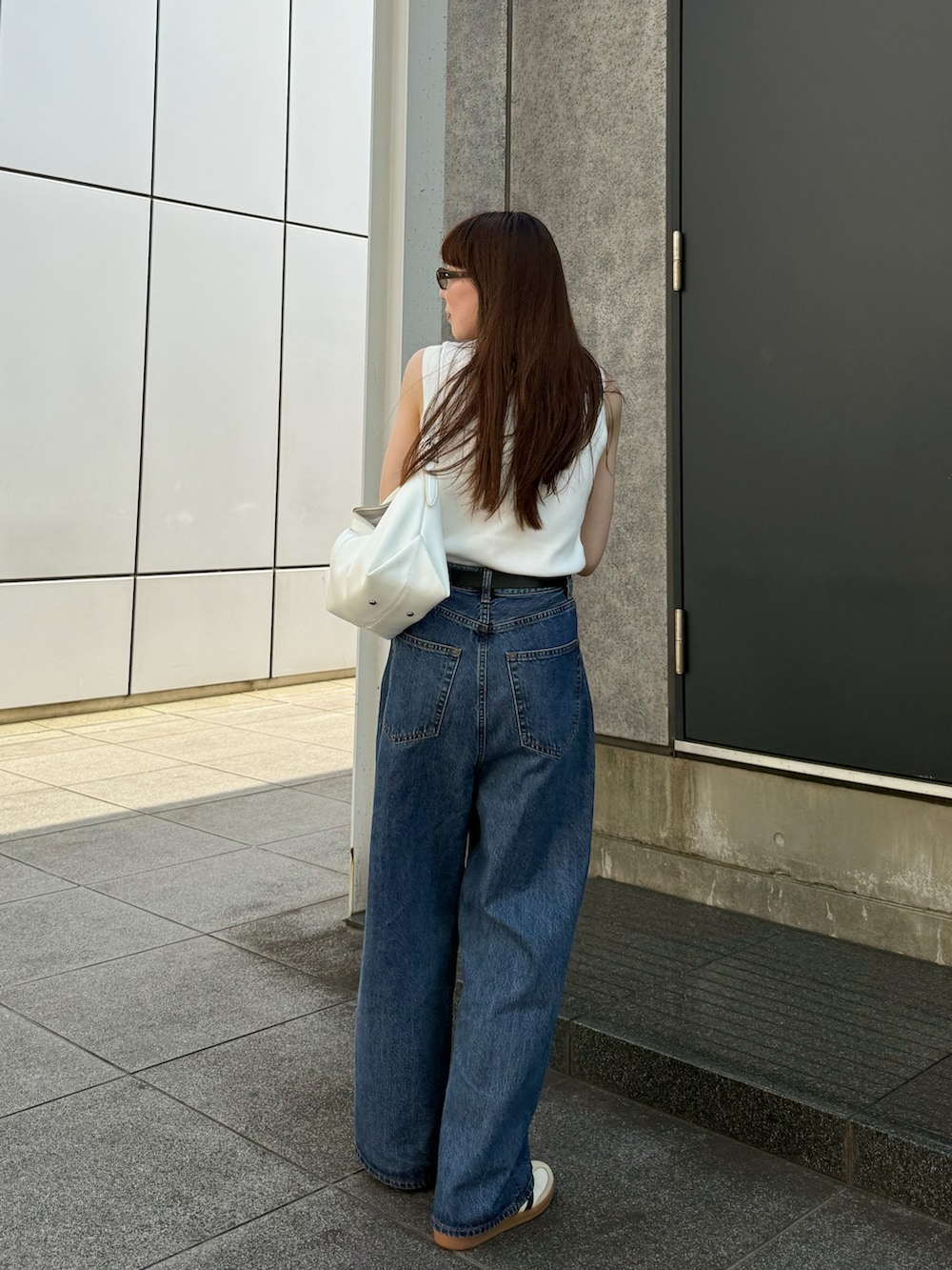 ホワイト系のタンクトップ、ブルー系のデニムパンツ、ホワイト系のスニーカーを着用したレディースの夏コーディネートの4枚目の写真