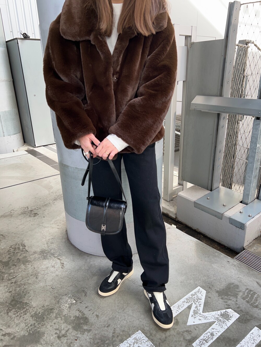 ブラウン系のブルゾン、ホワイト系のTシャツ/カットソー、ブラック系のショルダーバッグを着用したレディースの冬コーディネートの3枚目の写真