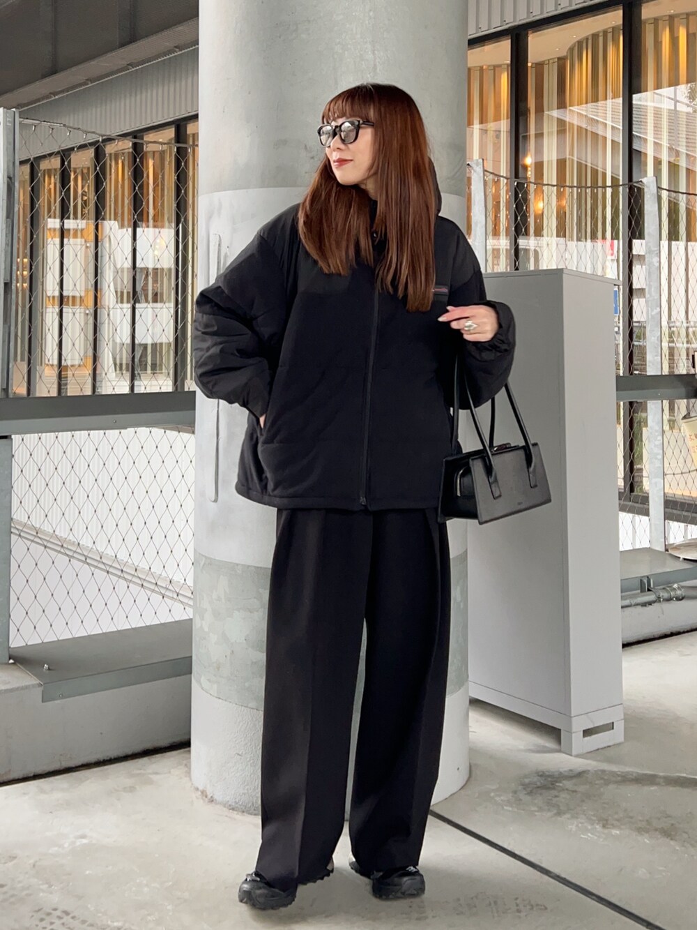 ブラック系のブルゾン、ブラック系のその他パンツ、ホワイト系のTシャツ/カットソーを着用したレディースの冬コーディネートの2枚目の写真