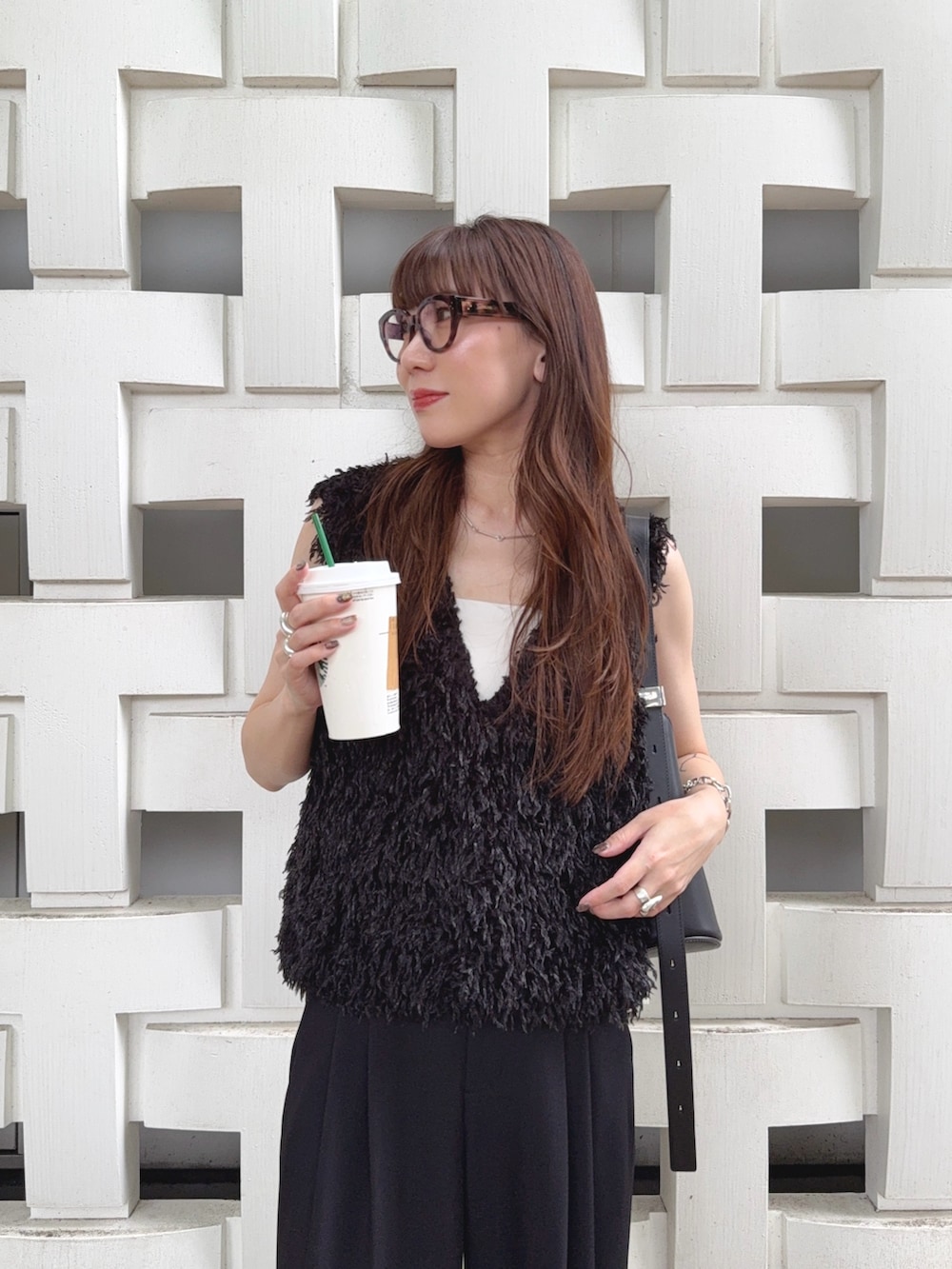 ブラック系のベスト、ブラック系のスラックス、ブラック系のバッグを着用したレディースの秋コーディネートの3枚目の写真