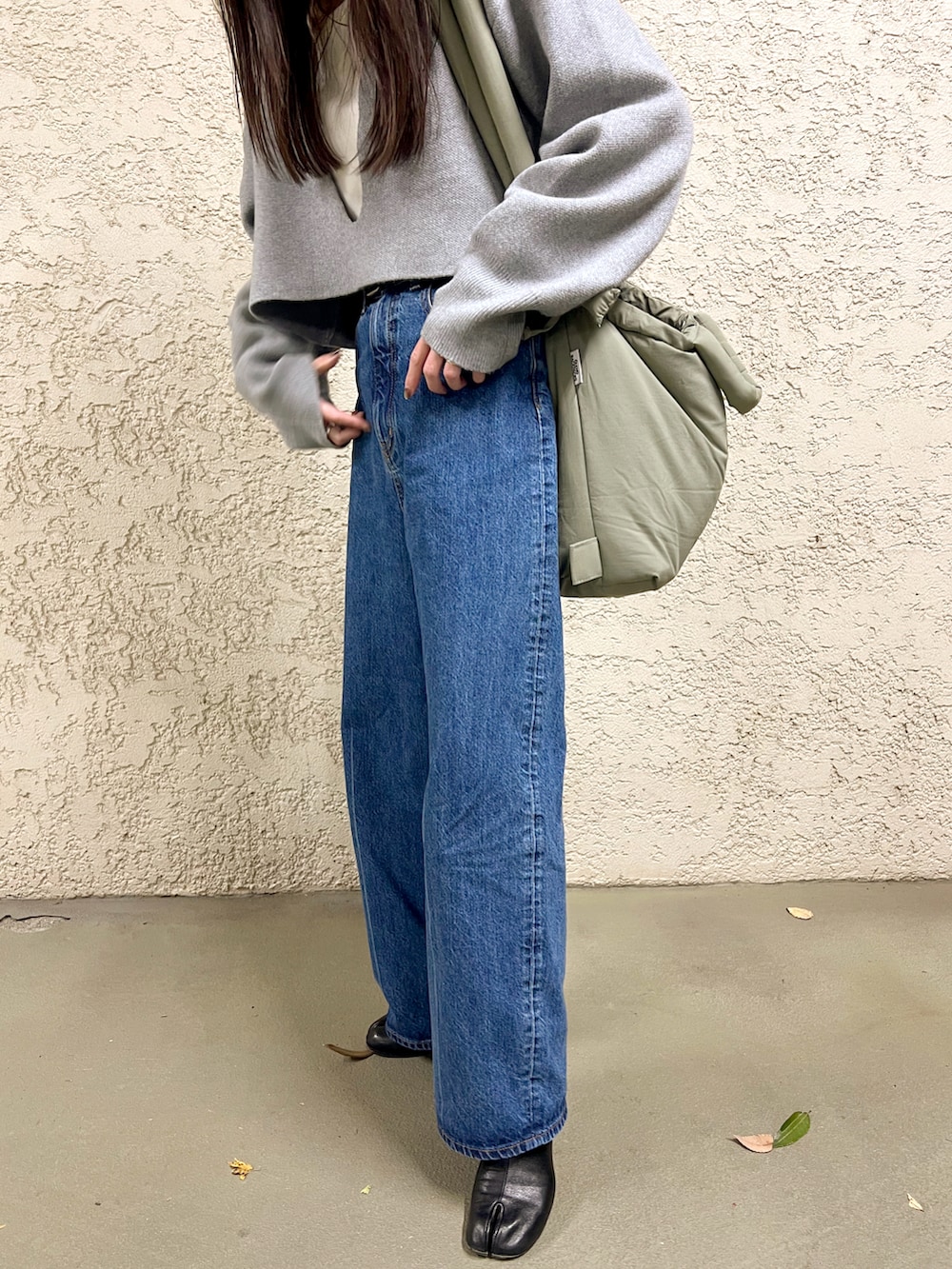 グレー系のニット/セーター、ブルー系のデニムパンツ、ブラック系のブーツを着用したレディースの冬コーディネートの5枚目の写真