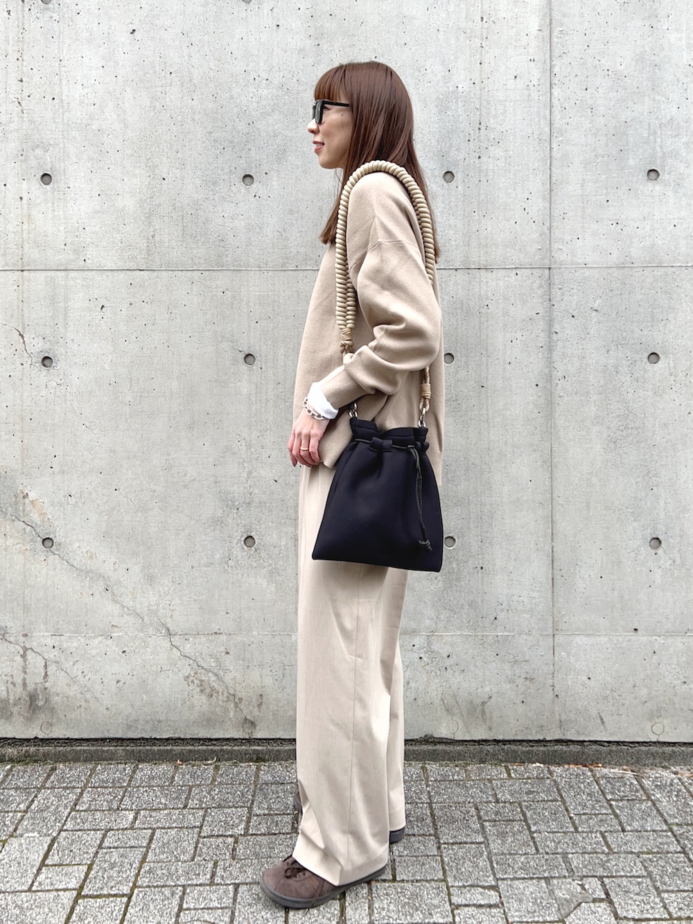 ベージュ系のトップス、ベージュ系のパンツ、ベージュ系のショルダーバッグを着用したレディースの冬コーディネートの3枚目の写真