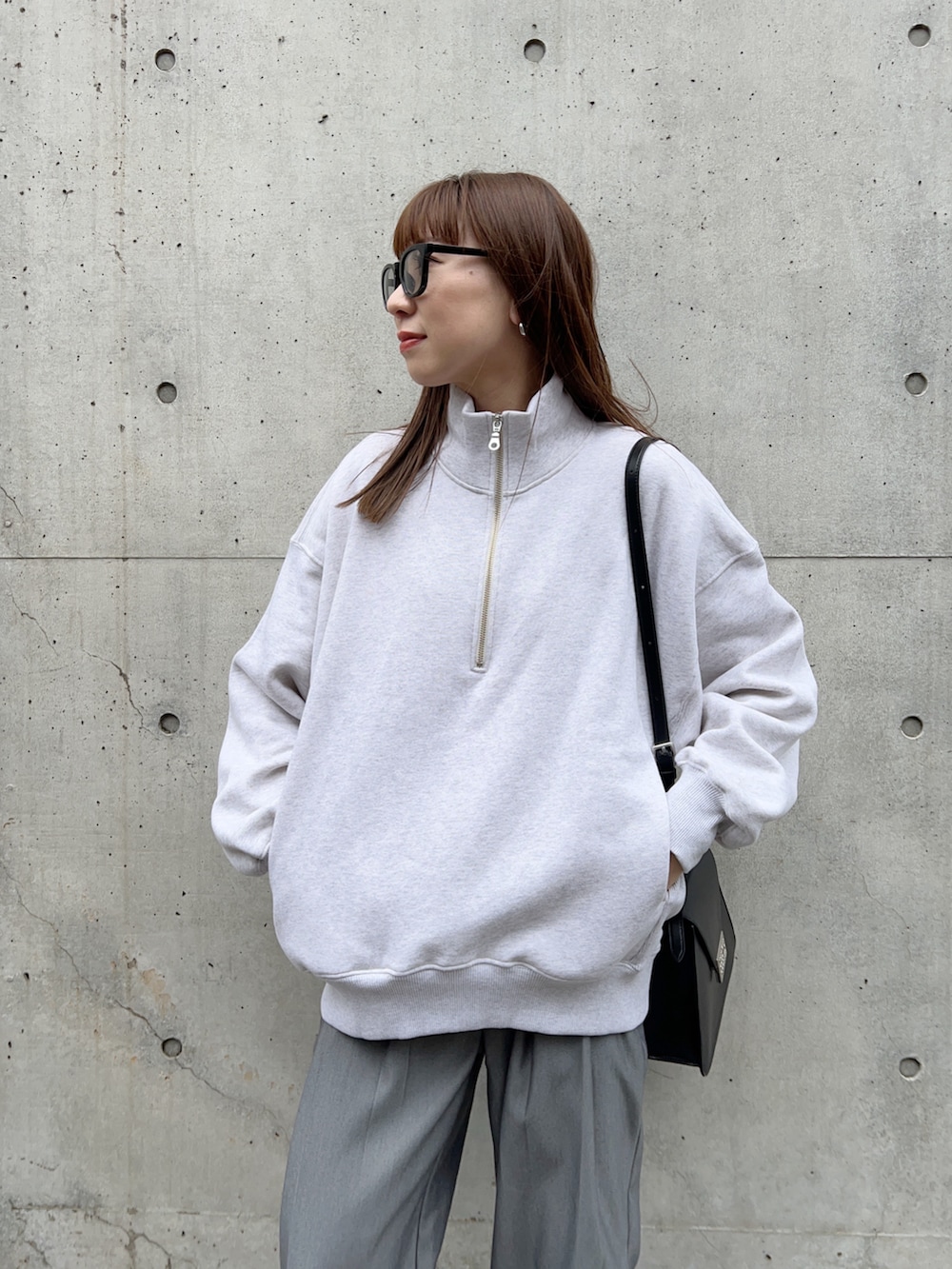 グレー系のスウェット、グレー系のスラックス、ブラック系のモカシン/デッキシューズを着用したレディースの冬コーディネートの3枚目の写真