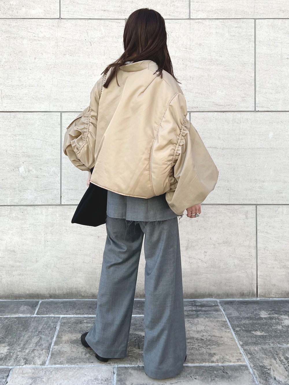 ベージュ系のMA-1、グレー系のスラックス、ブラック系のブーツを着用したレディースの秋コーディネートの4枚目の写真