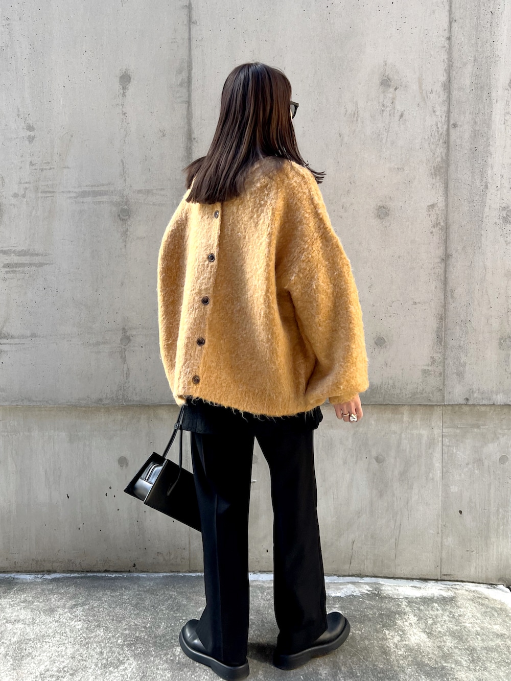 イエロー系のカーディガン/ボレロ、ブラック系のスラックス、ブラック系のハンドバッグを着用したレディースの秋コーディネートの5枚目の写真