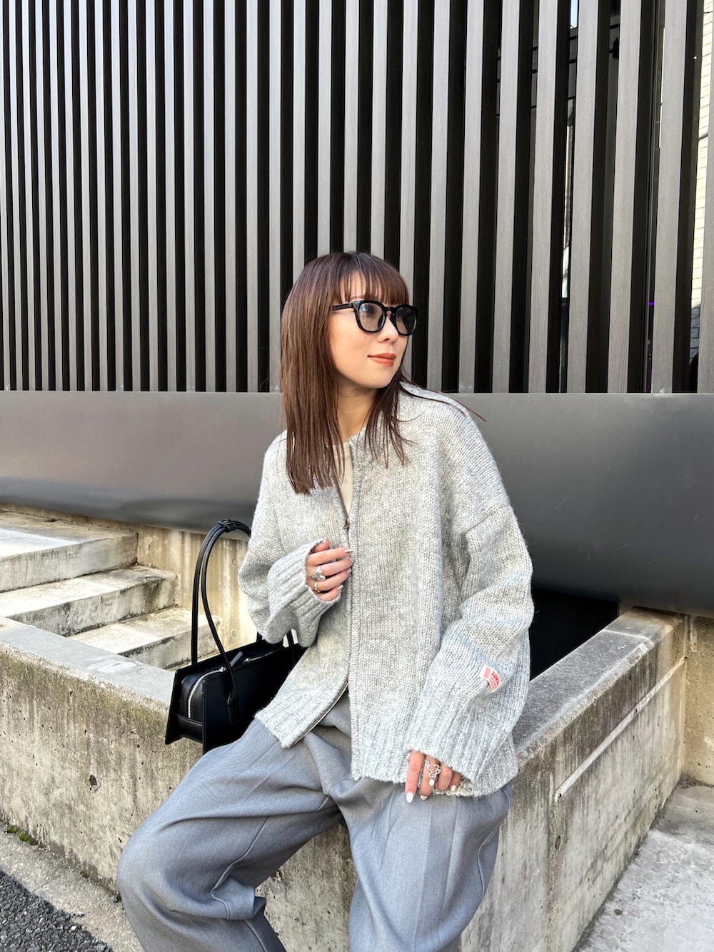 グレー系のニット/セーター、グレー系のスラックス、ブラック系のスニーカーを着用したレディースの秋コーディネートの5枚目の写真