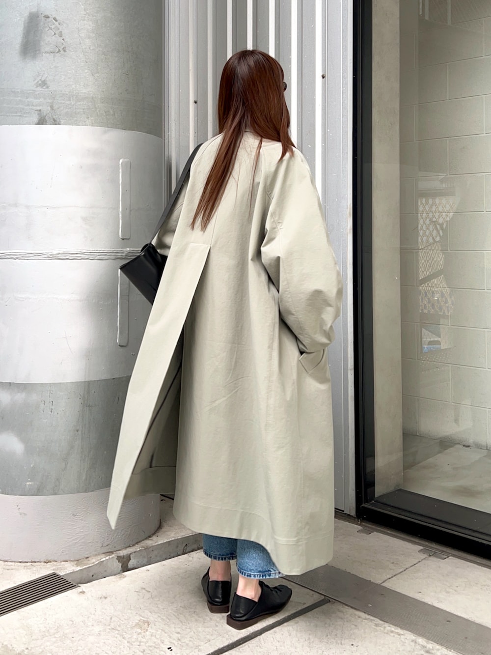 グリーン系のステンカラーコート、ホワイト系のTシャツ/カットソー、ブルー系のデニムパンツを着用したレディースの春コーディネートの3枚目の写真