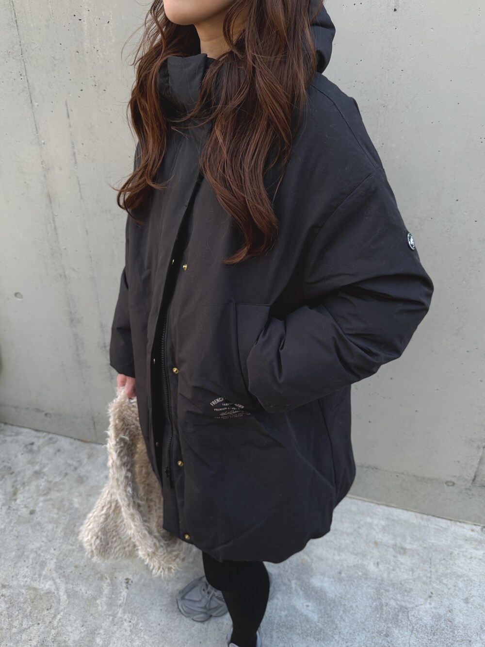 ブラック系のダウンジャケット/コート、ベージュ系のショルダーバッグ、グレー系のスニーカーを着用したレディースの冬コーディネートの5枚目の写真