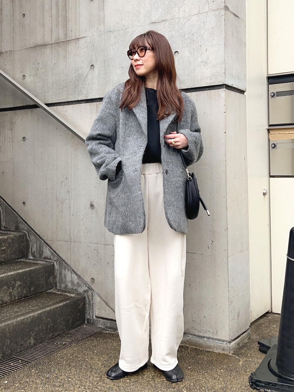 グレー系のテーラードジャケット、ホワイト系のスウェットパンツ、ブラック系のショルダーバッグを着用したレディースの冬コーディネートの2枚目の写真