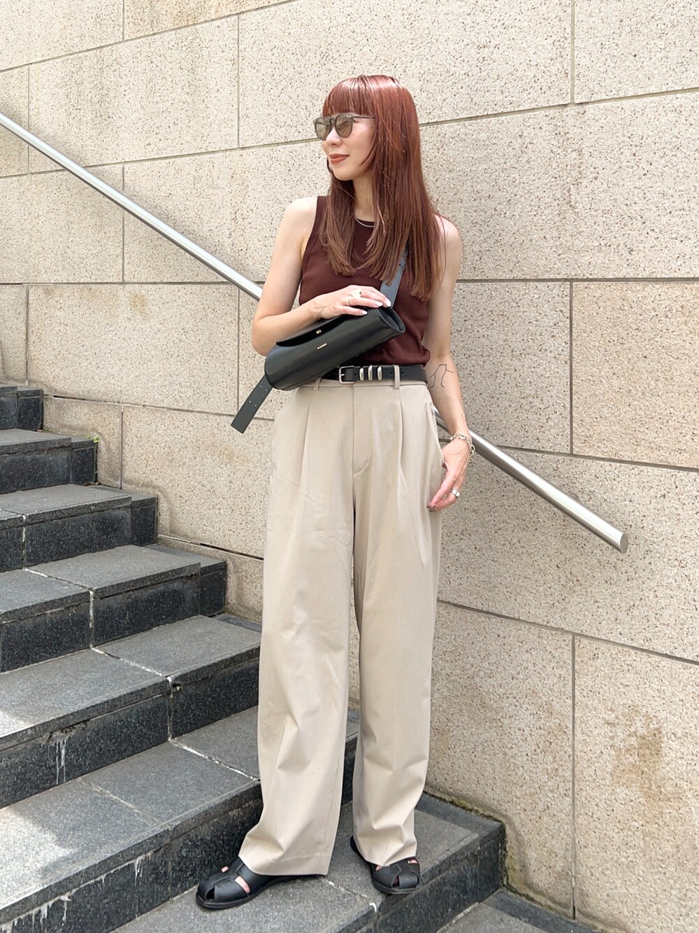ブラウン系のタンクトップ、ベージュ系のパンツ、ブラック系のショルダーバッグを着用したレディースの夏コーディネートの2枚目の写真
