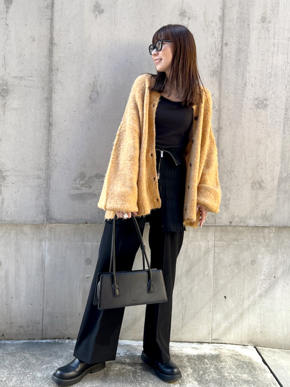 イエロー系のカーディガン/ボレロ、ブラック系のスラックス、ブラック系のハンドバッグを着用したレディースの秋コーディネートの3枚目の写真