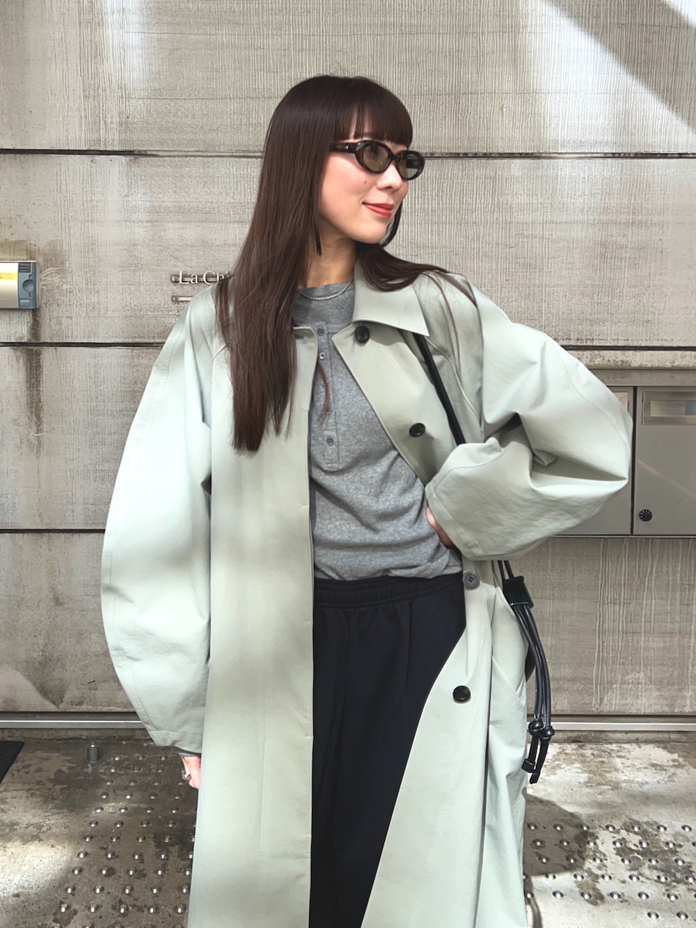 グリーン系のステンカラーコート、グレー系のTシャツ/カットソー、ブラック系のスウェットパンツを着用したレディースの春コーディネートの4枚目の写真