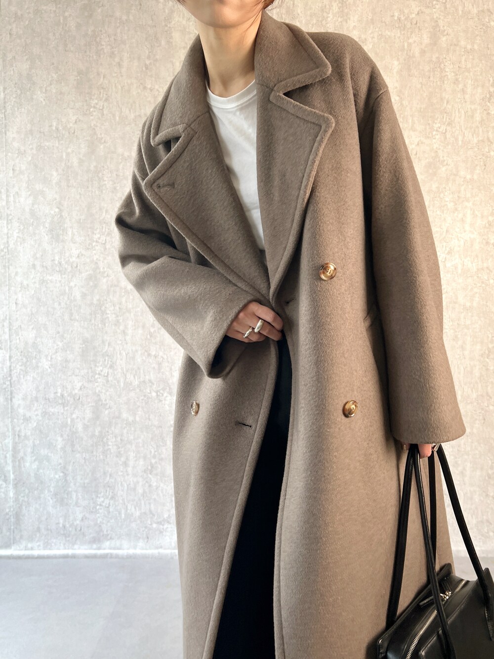 ブラウン系のチェスターコート、ブラック系のその他パンツ、ホワイト系のTシャツ/カットソーを着用したレディースの冬コーディネートの5枚目の写真