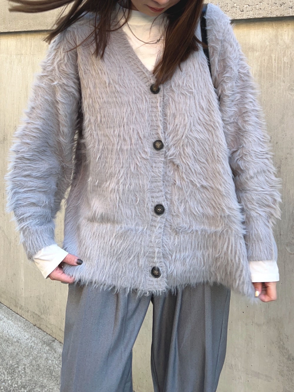 グレー系のカーディガン/ボレロ、ホワイト系のTシャツ/カットソー、ブラック系のショルダーバッグを着用したレディースの冬コーディネートの4枚目の写真