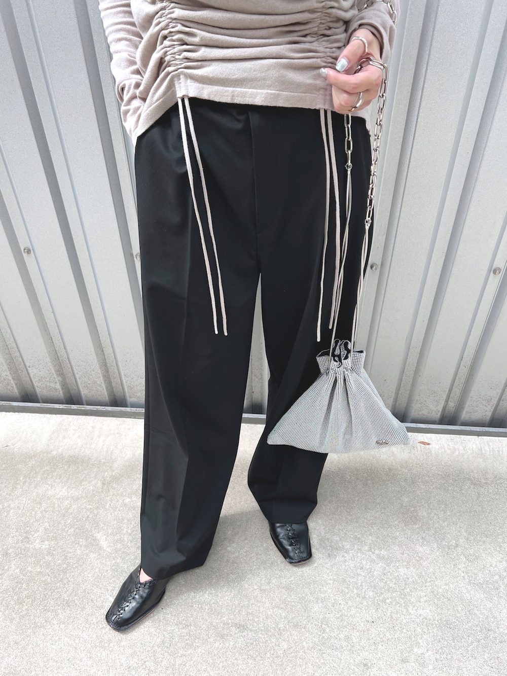 グレー系のニット/セーター、シルバー系のショルダーバッグ、ブラック系のパンツを着用したレディースの秋コーディネートの5枚目の写真