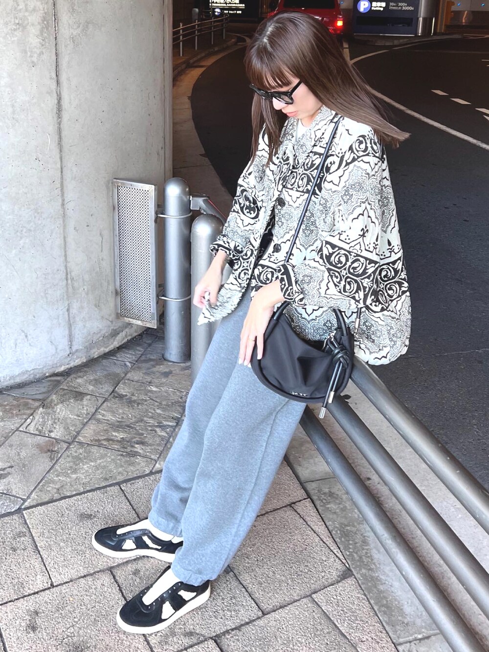 グレー系のパンツ、ブラック系のショルダーバッグ、ブラック系のスニーカーを着用したレディースの秋コーディネートの3枚目の写真