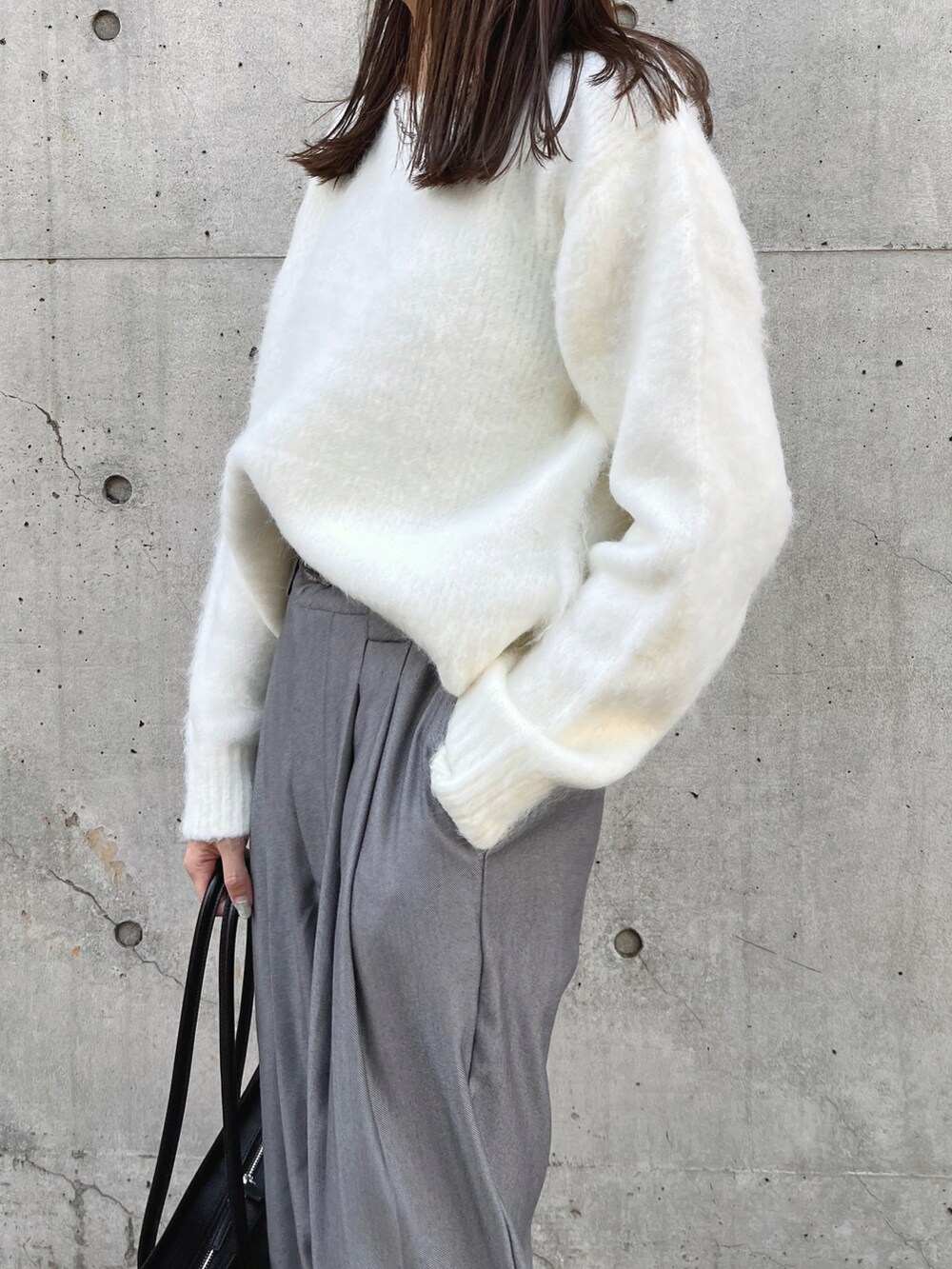 ホワイト系のニット/セーター、グレー系のスラックス、ブラック系のハンドバッグを着用したレディースの秋コーディネートの3枚目の写真