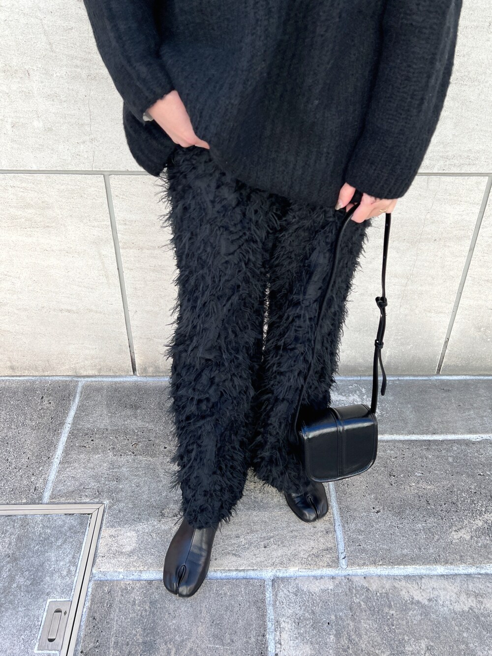 ホワイト系のTシャツ/カットソー、ブラック系のニット/セーター、ブラック系のショルダーバッグを着用したレディースの冬コーディネートの5枚目の写真