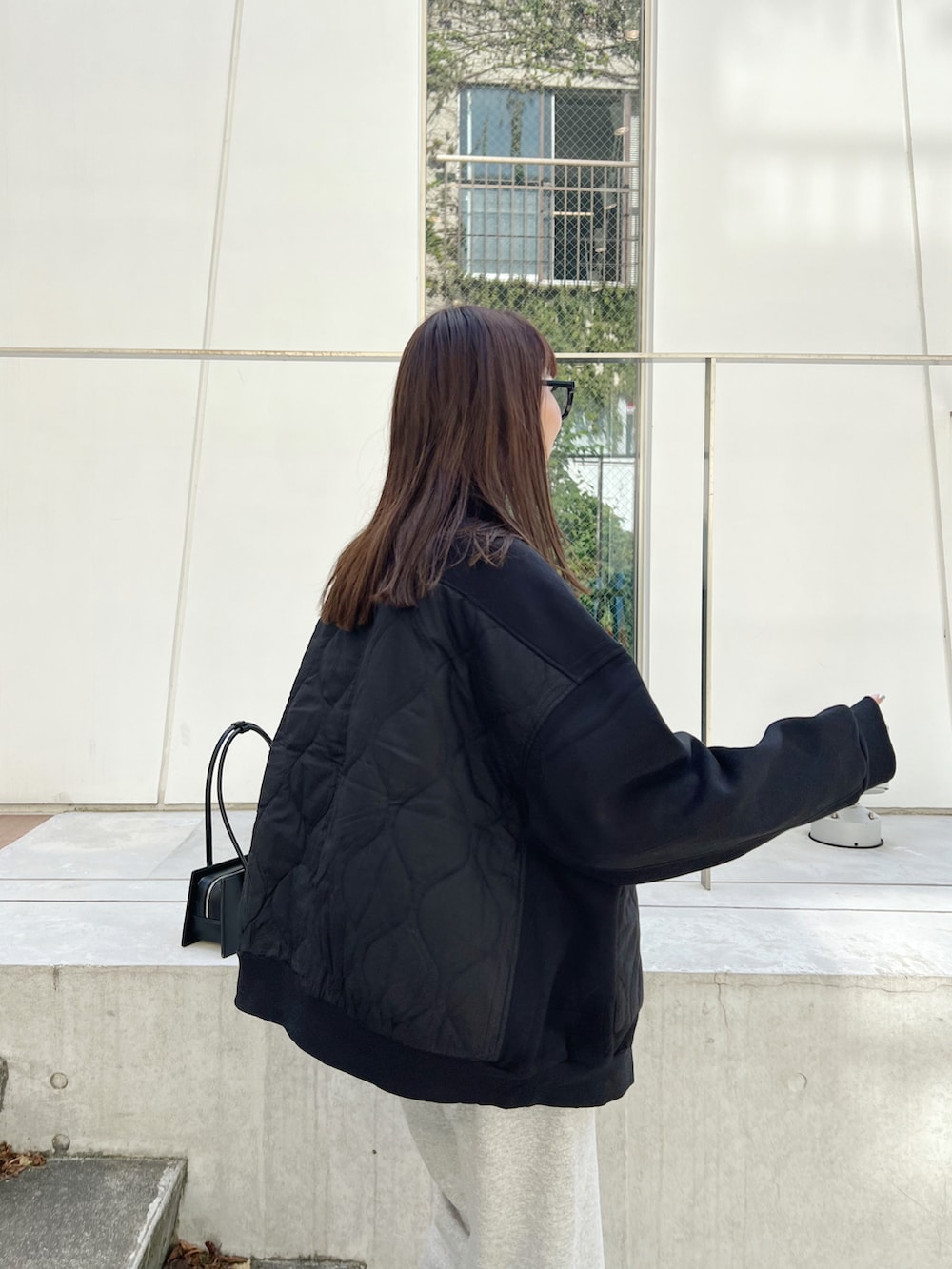 ブラック系のブルゾン、グレー系のスウェットパンツ、ブラック系のハンドバッグを着用したレディースの秋コーディネートの4枚目の写真