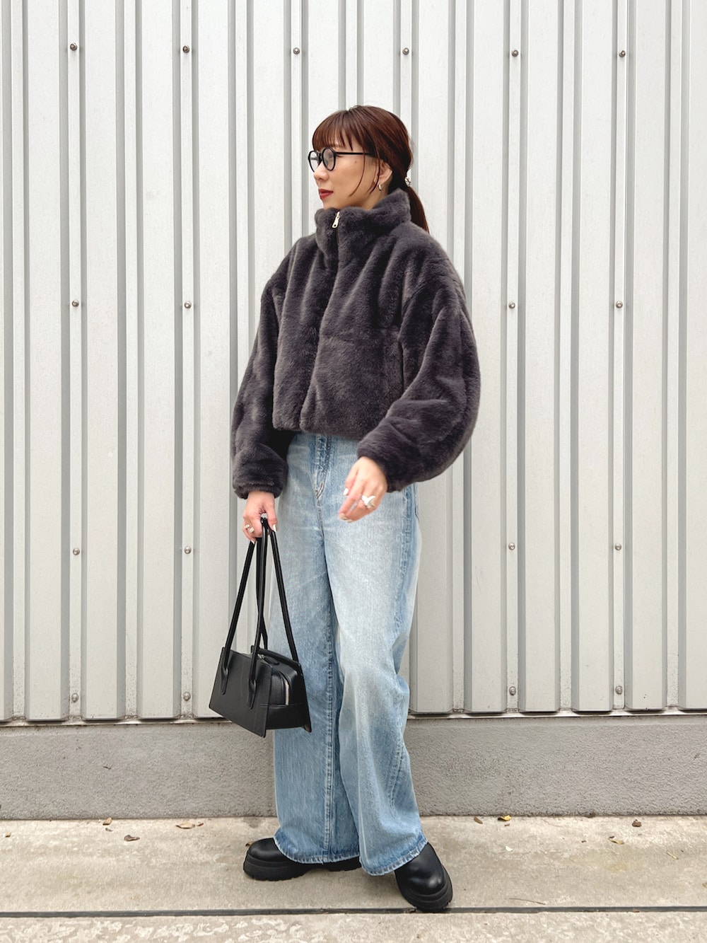 グレー系のブルゾン、ブルー系のデニムパンツ、ブラック系のブーツを着用したレディースの秋コーディネートの2枚目の写真