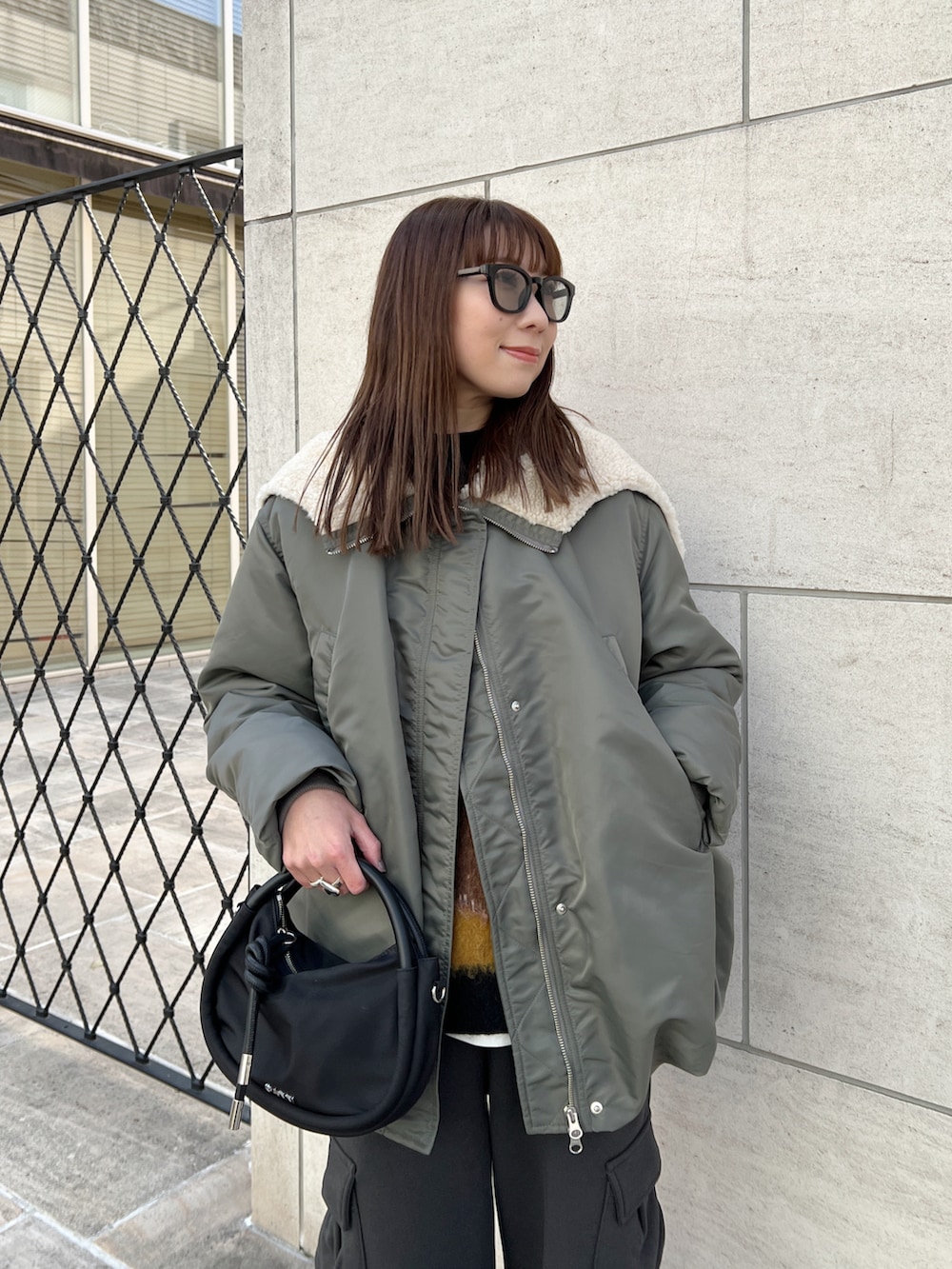 グリーン系のブルゾン、ブラック系のニット/セーター、グレー系のカーゴパンツを着用したレディースの冬コーディネートの4枚目の写真