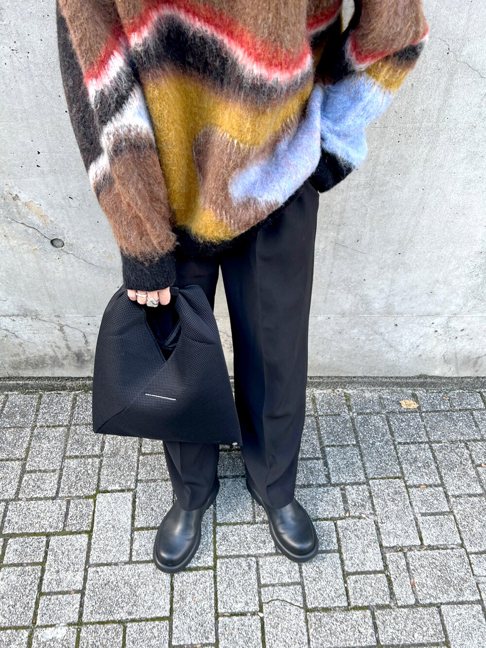 ブラック系のニット/セーター、ブラック系のトートバッグ、ブラック系のスラックスを着用したレディースの秋コーディネートの5枚目の写真