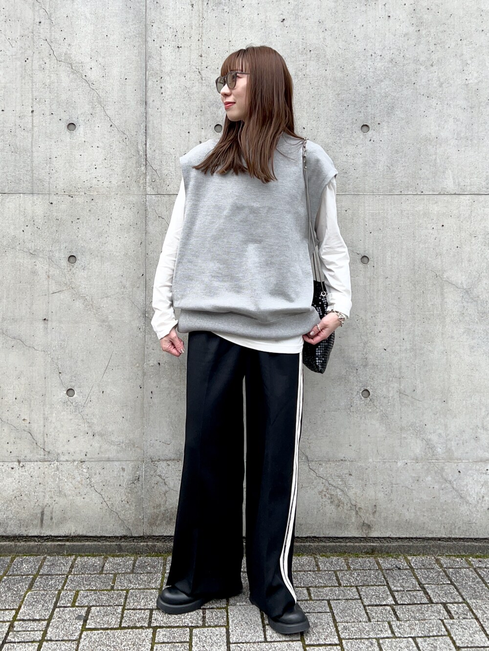 ホワイト系のTシャツ/カットソー、グレー系のニット/セーター、ブラック系のスラックスを着用したレディースの春コーディネートの2枚目の写真