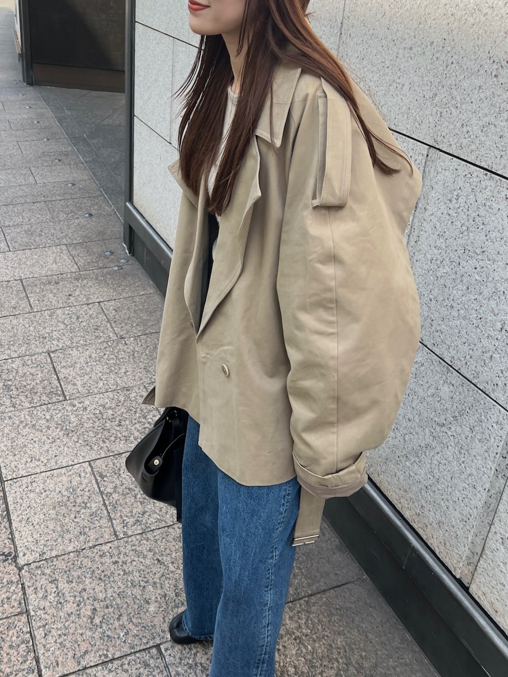 ベージュ系のトレンチコート、ブルー系のデニムパンツ、ブラック系のブーツを着用したレディースの春コーディネートの3枚目の写真