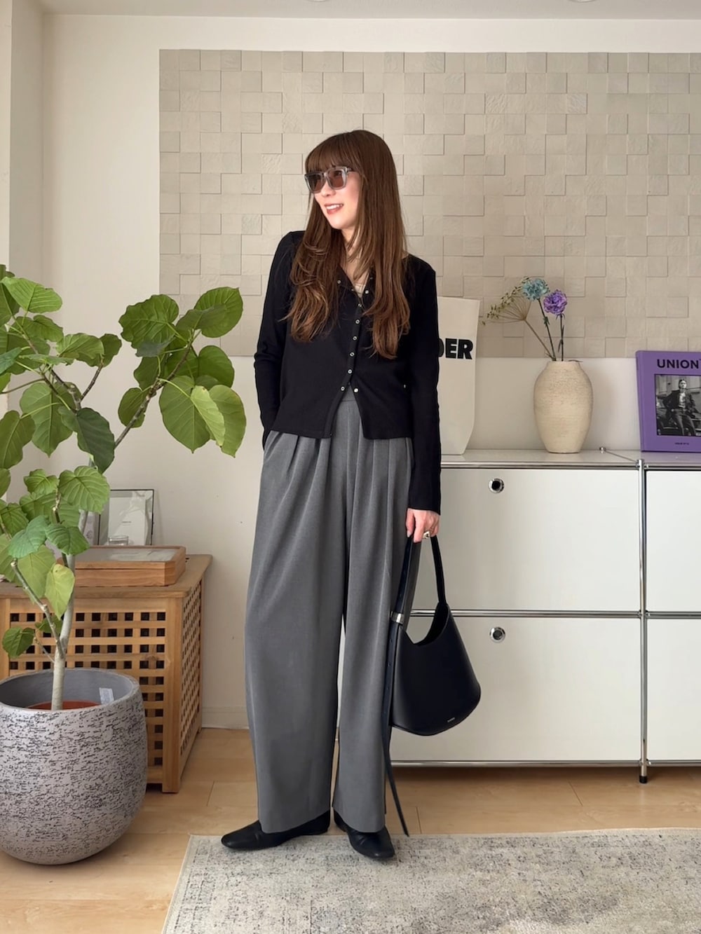 ブラック系のカーディガン/ボレロ、グレー系のスラックス、ブラック系のスリッポンを着用したレディースの春コーディネートの2枚目の写真