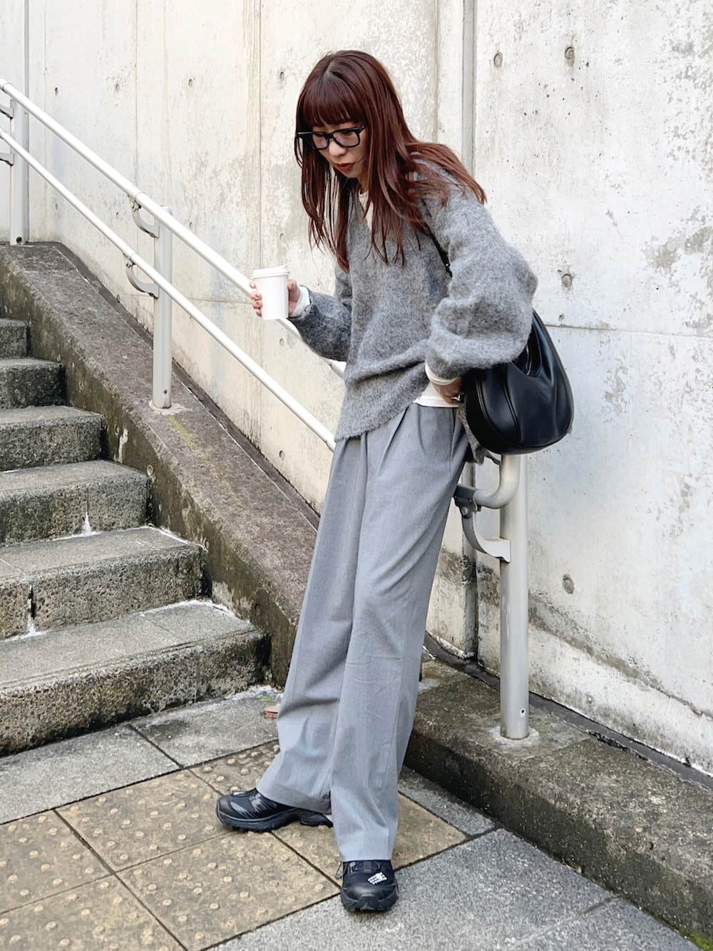 グレー系のニット/セーター、ホワイト系のTシャツ/カットソー、グレー系のパンツを着用したレディースの秋コーディネートの2枚目の写真