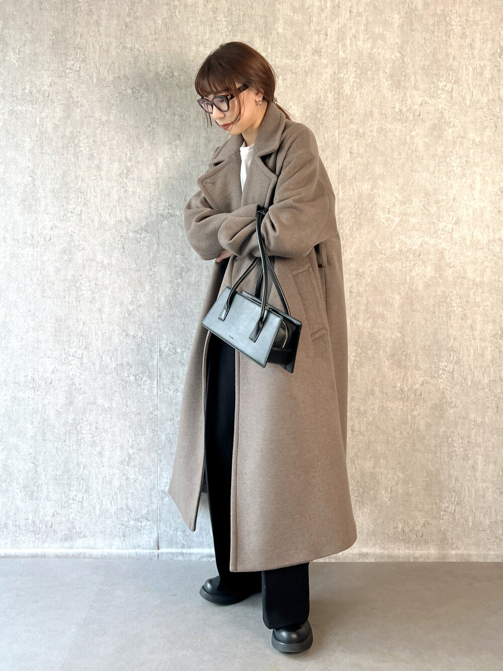 ブラウン系のチェスターコート、ブラック系のその他パンツ、ホワイト系のTシャツ/カットソーを着用したレディースの冬コーディネートの2枚目の写真