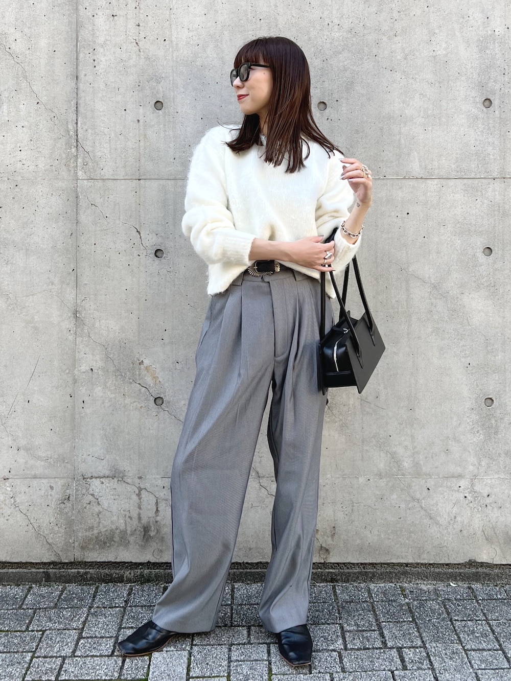ホワイト系のニット/セーター、グレー系のスラックス、ブラック系のハンドバッグを着用したレディースの秋コーディネートの2枚目の写真