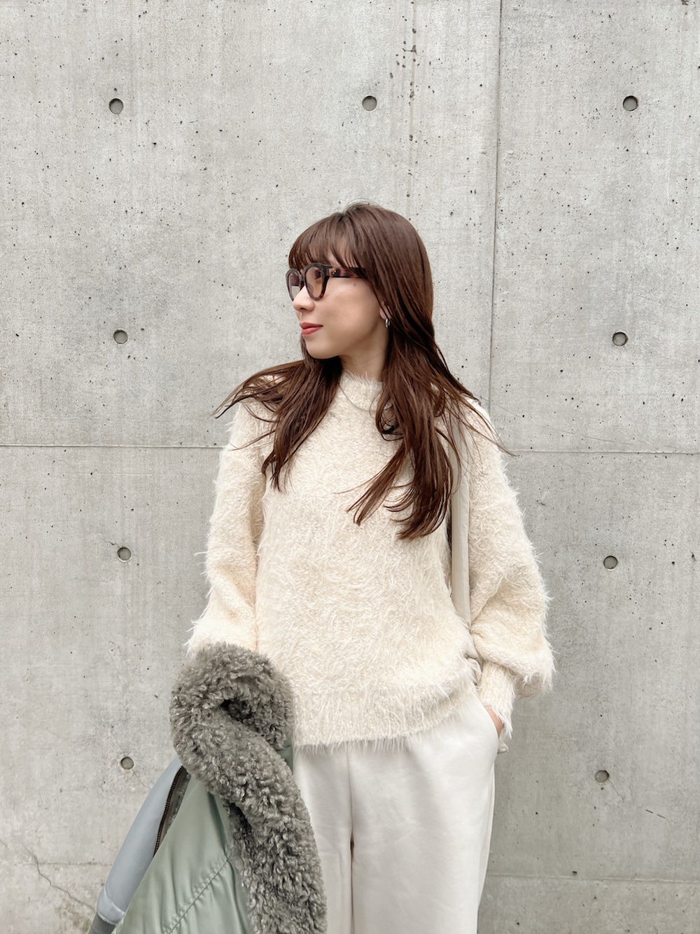 グリーン系のMA-1、ホワイト系のニット/セーター、ホワイト系のスウェットパンツを着用したレディースの冬コーディネートの4枚目の写真