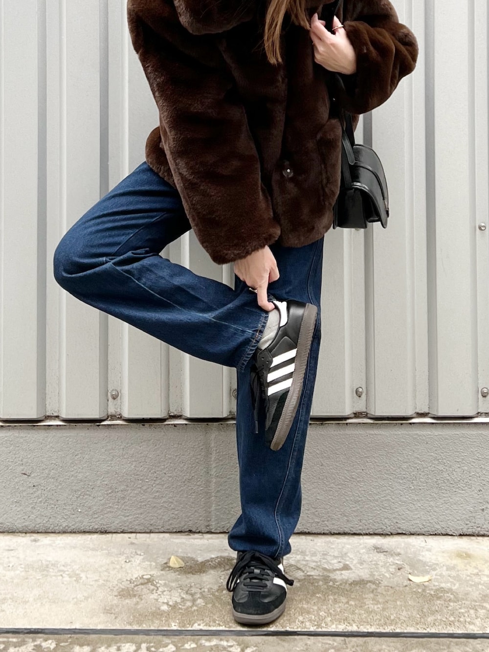 ブラウン系のブルゾン、ブルー系のデニムパンツ、ブラック系のスニーカーを着用したレディースの冬コーディネートの5枚目の写真