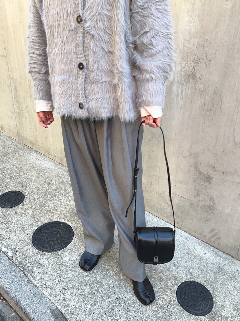 グレー系のカーディガン/ボレロ、ホワイト系のTシャツ/カットソー、ブラック系のショルダーバッグを着用したレディースの冬コーディネートの5枚目の写真