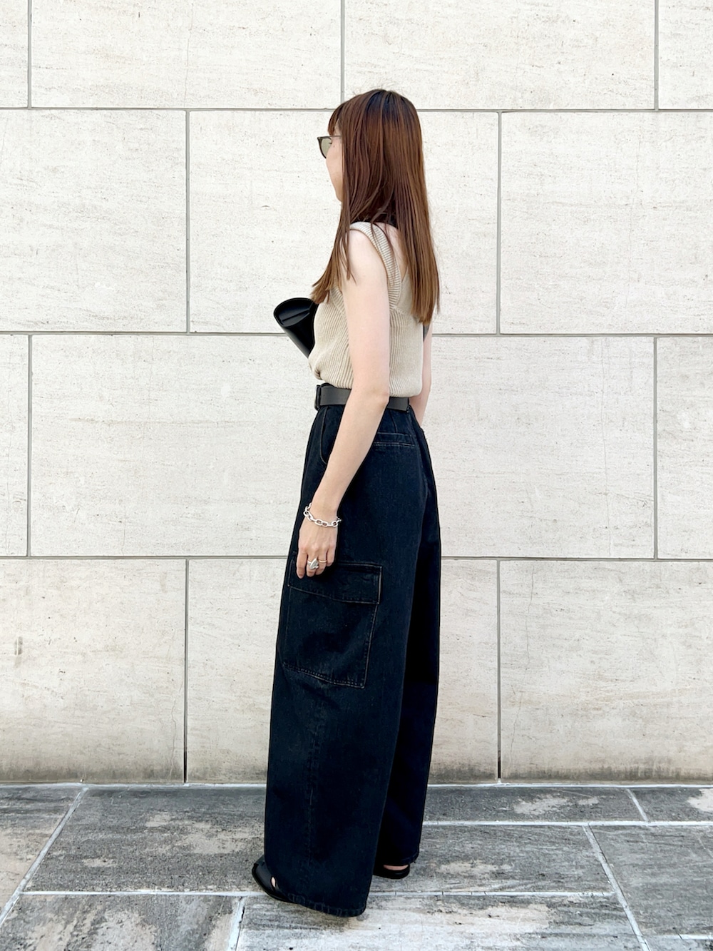 ベージュ系のニット/セーター、グレー系のデニムパンツ、ブラック系のショルダーバッグを着用したレディースの夏コーディネートの3枚目の写真