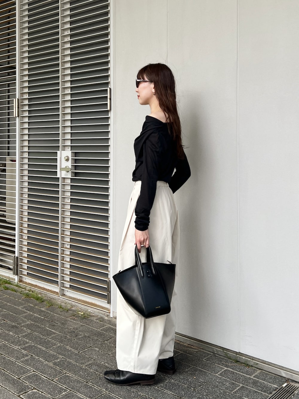 ブラック系のTシャツ/カットソー、ホワイト系のその他パンツ、ブラック系のバッグを着用したレディースの春コーディネートの4枚目の写真