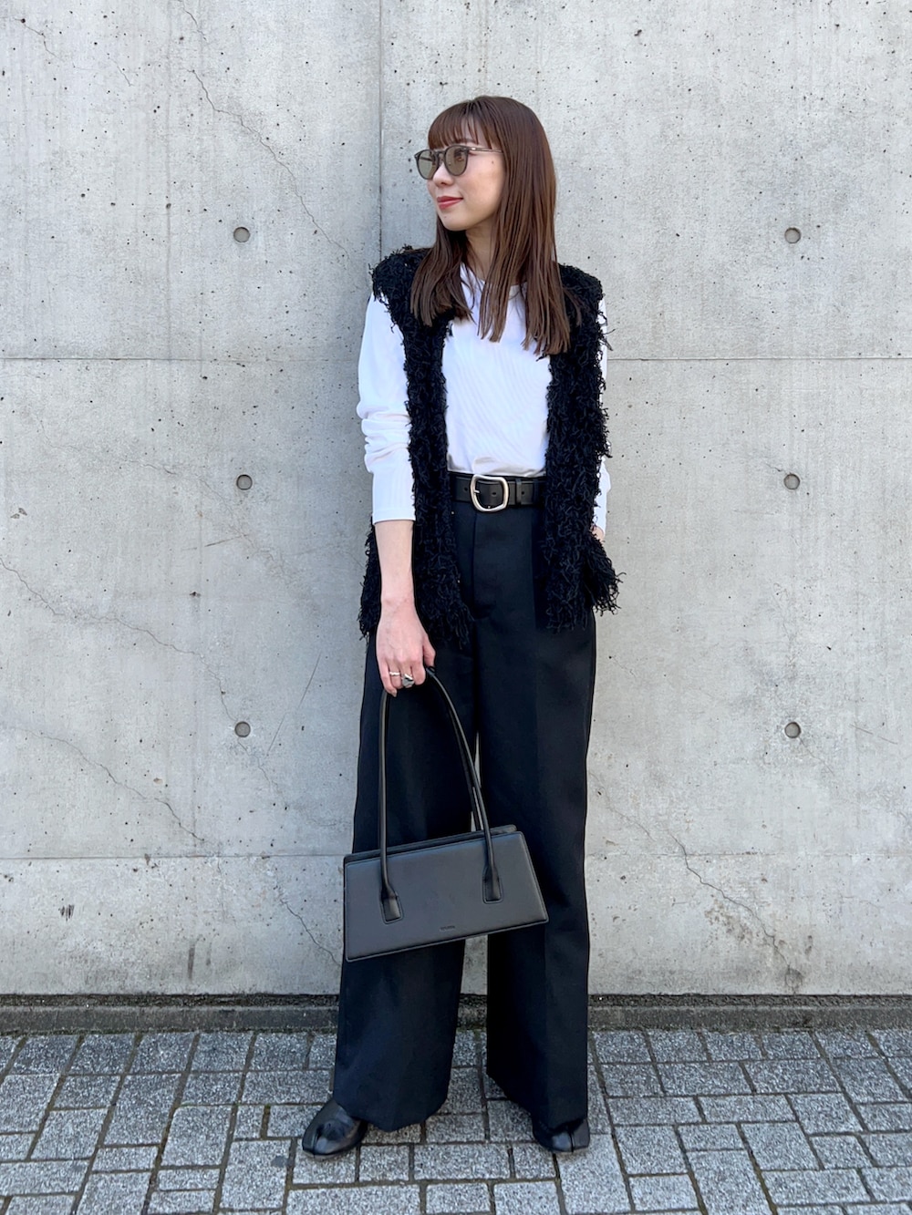 ブラック系のベスト、グレー系のその他パンツ、ブラック系のブーツを着用したレディースの春コーディネートの2枚目の写真