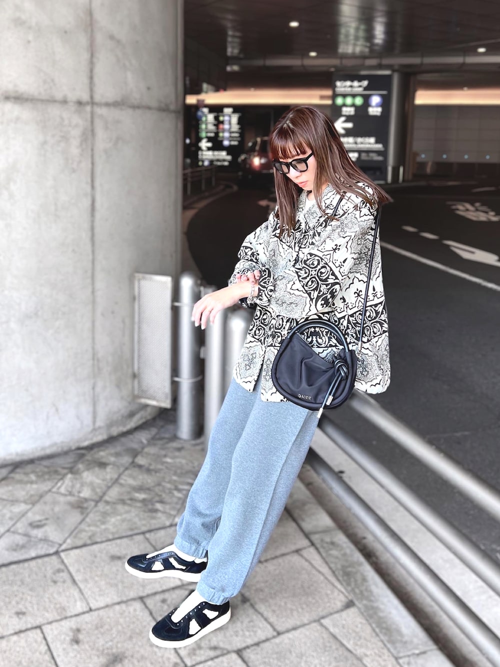 グレー系のパンツ、ブラック系のショルダーバッグ、ブラック系のスニーカーを着用したレディースの秋コーディネートの2枚目の写真